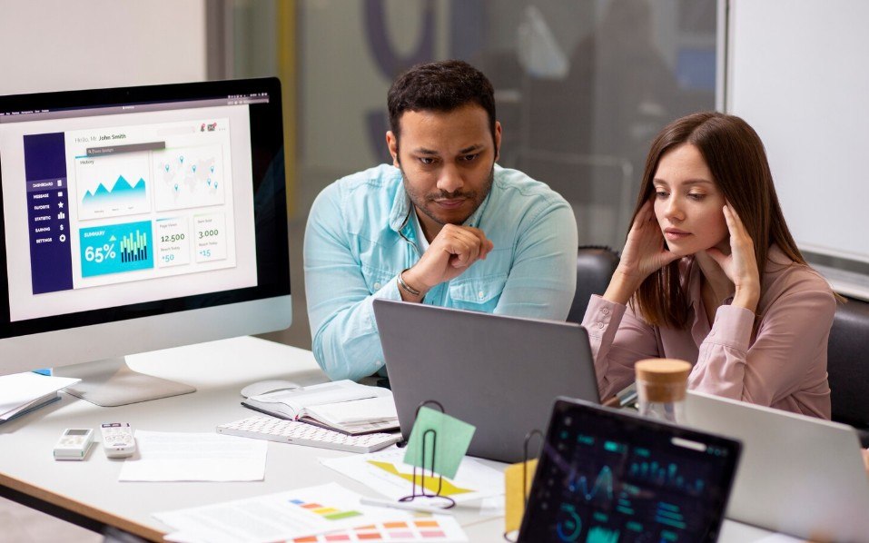 A team reviewing website performance dashboards on a monitor and laptops