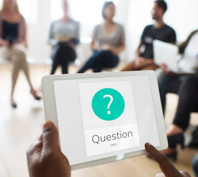 A person tapping a Question prompt on a tablet during a group discussion