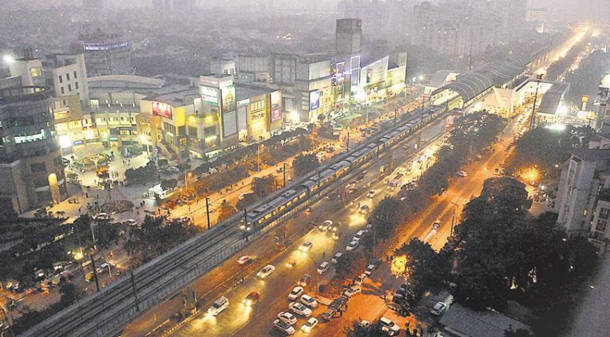 An aerial night view of MG Road, Gurgaon, with the metro line running alongside busy traffic