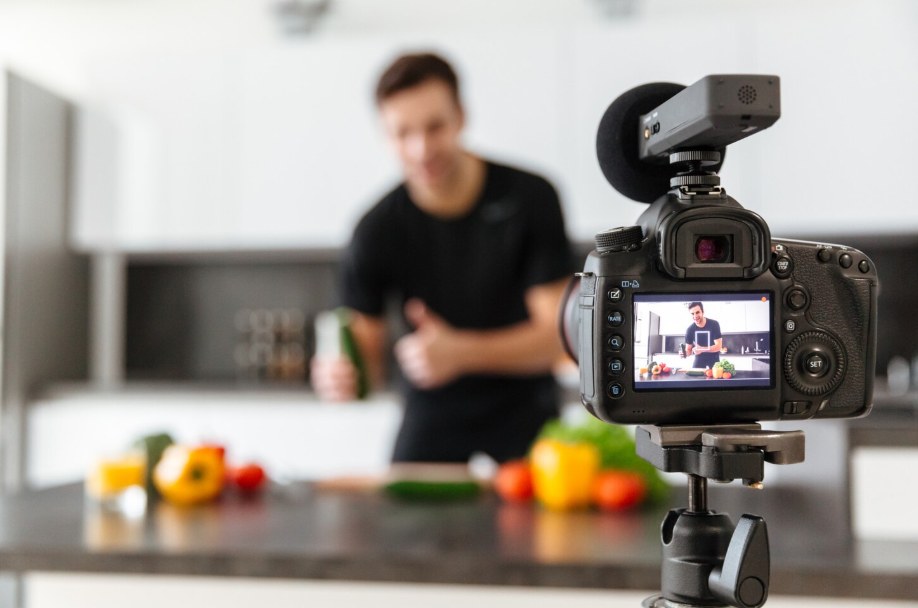 A camera filming a man presenting a product in a kitchen setting