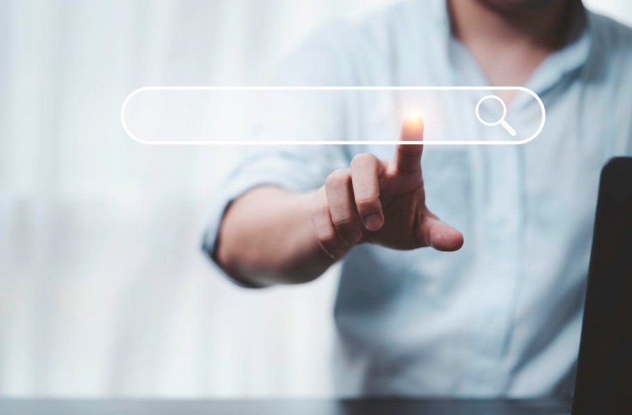 A hand tapping a digital search bar, representing search engine marketing